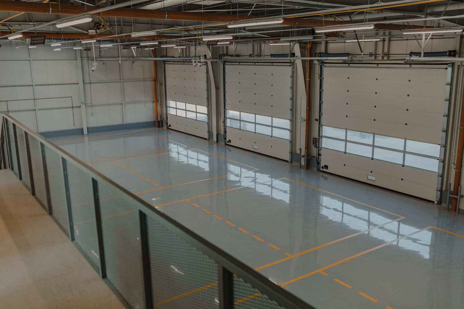 Industrial building with overhead doors and yellow safety lines on a coated floor